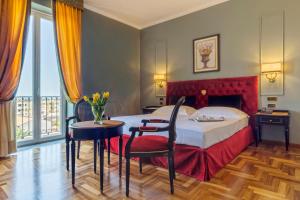 锡拉库扎波利蒂别墅大酒店的酒店客房带一张床、一张桌子和椅子