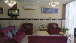 马斯喀特فندق الخليج للشقق الفندقية GULF HOTEL APARTMENTS的一间设有紫色长沙发、椅子和吊灯的等候室
