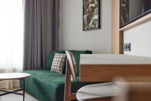 库雷萨雷乔治奥特斯温泉酒店的客厅配有绿色沙发和桌子