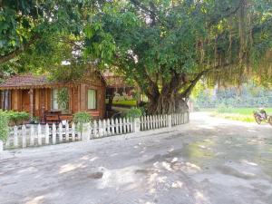 宁平Tam Coc Sunshine Homestay的一座木房子,有树和栅栏