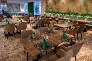 希欧福克蓝色高级酒店的餐厅设有木桌、椅子和绿色餐巾