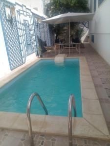 苏塞Dar Sarra的蓝色的游泳池,配有遮阳伞和桌子
