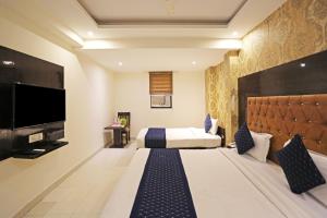 新德里The Rose Manor By Iconic Delhi International Airport的配有一张床和一台平面电视的酒店客房