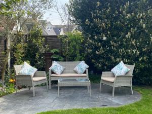 HadleighRooms in Hadleigh,Essex的庭院里配有3把藤椅和枕头