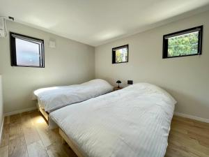 汤泽町Spruce Cottage的带2扇窗户的客房内的2张床