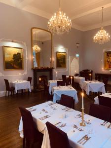 Kinnitty基尼缇城堡酒店的用餐室配有白色桌椅和吊灯。