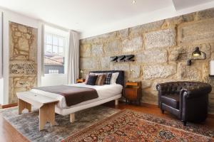 波尔图波尔图雅致舒适一室公寓酒店的一间卧室设有一张床和石墙