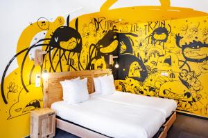 斯特拉斯堡戈拉法尔加酒店的一间卧室设有黄色的墙壁、一张床和一幅画