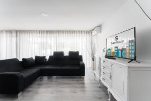 加亚新城GuestReady - Amazing holiday home near the beach的客厅配有黑色沙发和平面电视。