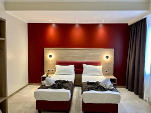 米兰Hotel Giacosa的红色墙壁的客房内的两张床