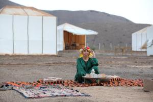 马拉喀什la casa de othmane的坐在毯子上,拿着一盘食物的女人