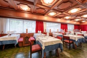 坎皮泰洛迪法萨葛罗曼酒店的一间设有白色桌椅和红色窗帘的餐厅