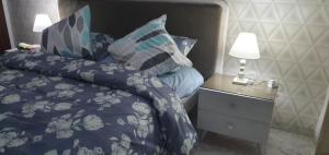 拉古莱特LUX & VIP apartment at Berges du Lac 2 Tunis的一张带蓝色棉被的床和一个带灯的床头柜