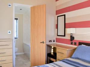 LlanddulasVictory Lodge 2 Bedroom - Sleeps 6 - Bron-Y-Wendon Holiday Park的一间带一张床和一张书桌的卧室以及一间浴室。