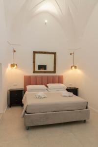 奥斯图尼Palazzo AD 1892 - SUITES & SPA的一间卧室设有两张床,墙上设有一面镜子