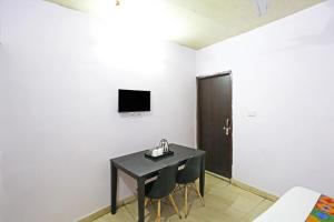 新德里Twamev Punjabi Bagh的一间设有黑色桌子、椅子和电视的客房