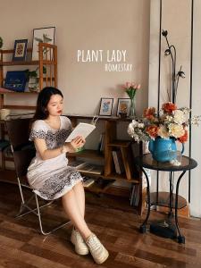 高平Plant Lady Homestay Cao Bằng的坐在椅子上读书的女人