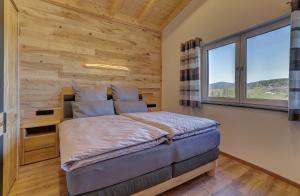 EppenschlagLandhaus Rachelblick的一间卧室设有木墙和一张带窗户的床