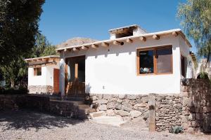 蒂尔卡拉Cabañas Tilcara Taki的白色的小房子,有石墙