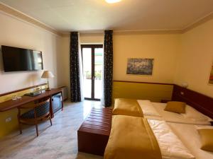 巴多利诺Hotel Villa Olivo Resort 3S的酒店客房设有两张床、一张桌子和一台电视。