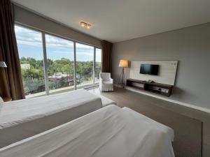 皮纳马尔Hotel Zentiva Pinamar的酒店客房设有两张床和一台平面电视。