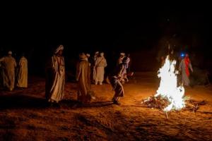 MhamidMhamid Luxury Camp的一群人晚上站在 ⁇ 火旁