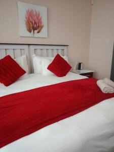 东伦敦Edladleni Guesthouse Quigney的卧室配有白色床铺上的红色毯子