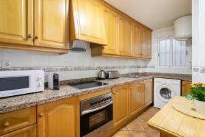 圣波拉Precioso apartamento的厨房配有木制橱柜、水槽和微波炉