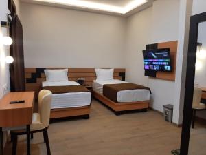 日惹Griya Endika Syariah的客房设有两张床、一张桌子和一台电视机。