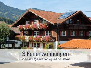 博尔斯特尔朗Biohof Burger, 3 sonnige Fewo, alle mit Balkon, Spielzimmer, Grillhütte, 7 km vor Oberstdorf的一座花卉和太阳能板的房子