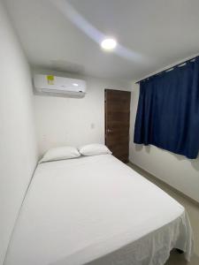 卡塔赫纳HOTEL DI MAR的卧室配有白色的床和蓝色窗帘