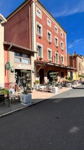罗纳河畔的图尔农Logis Hôtel Restaurant Azalées的街道上一座带桌椅的大型砖砌建筑