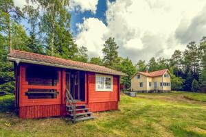 基尔科努米Villa Porkkala - Seafront Jacuzzi Nature Reserve的一座位于庭院的红色小屋,后面有一座房子