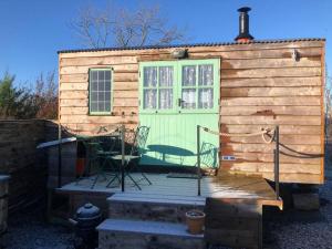 BottesfordShepherd’s Hut with complete privacy的一座小房子,有绿门和椅子