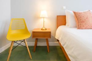 波尔图Alegria Colour Apartments的床边的黄椅和床头柜