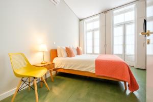 波尔图Alegria Colour Apartments的一间卧室配有一张床和一张黄色椅子