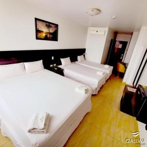 普卡尔帕Qallwa Pucallpa的配有白色床单的酒店客房内的两张床