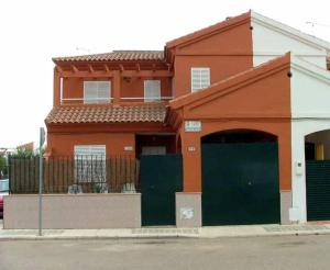 贝纳卡松"Casa Colorá" en Sevilla的一座橙色的建筑,设有绿门和栅栏