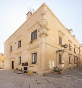 莱切Palazzo Personè Dimora Storica的一座大型石头建筑,前面设有黄色椅子