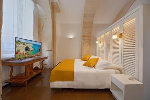 莱切Palazzo Personè Dimora Storica的一间卧室配有一张床和一张书桌及电视