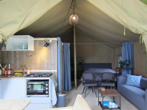 HensbroekLuxe safaritent op Landgoed de Leijen的帐篷设有厨房和客厅