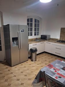 德朗西Jolie demeure proche stade de France的厨房配有不锈钢冰箱和桌子