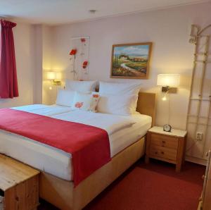 比绍夫斯韦尔达Logis L Auberge Gutshof的一间卧室配有一张带红色毯子的大床