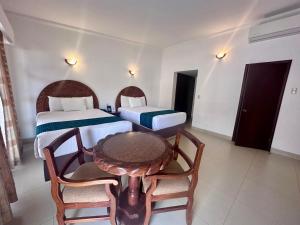 库利亚坎InHouse Select Hacienda Tres Rios的一间设有两张床和一张桌子及椅子的房间