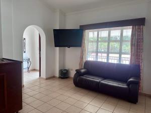 库利亚坎InHouse Select Hacienda Tres Rios的客厅配有黑色真皮沙发和窗户