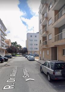 阿威罗Lovely Apartment Aveiro的一条街道,汽车停在大楼的一侧