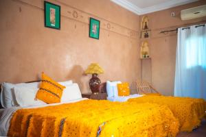 瓦尔扎扎特古堡卡斯巴酒店的一间卧室配有两张带橙色床单和灯的床