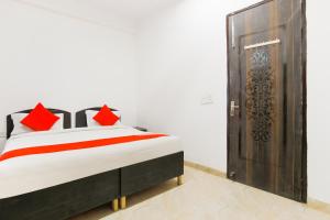 古尔冈OYO Welcome Residency的一间卧室配有一张带红色枕头的床和木门