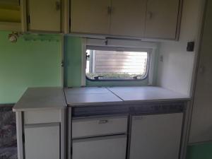 RouveenCaravan Vlinder的一个带柜台和窗户的小厨房