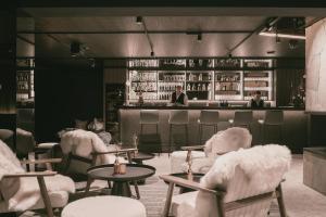 茵特斯托德TRIFORÊT alpinresort的一间设有白色椅子的餐厅和一间酒吧